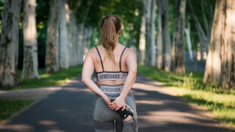 Personne s'étirant dans une allée bordée d'arbres