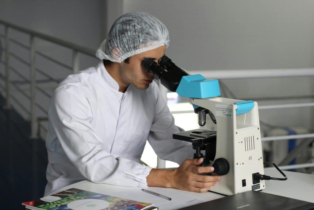 Scientifique en blouse blanche observant au microscope dans un laboratoire